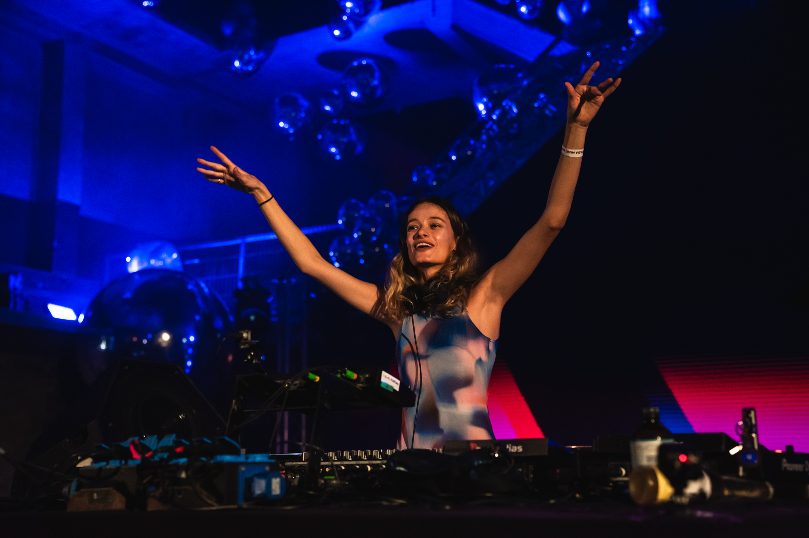 DJ arms up behind decks